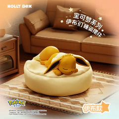 Boîte surprise Eeveelution endormie mettant en vedette une figurine Eevee endormie sur un coussin dans un décor douillet.