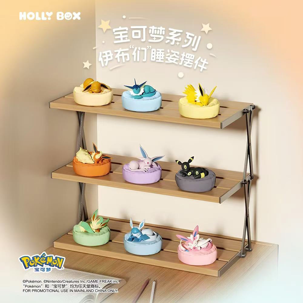 Boîte surprise Eeveelution endormie mettant en vedette des figurines Eeveelution colorées et des coussins assortis exposés.