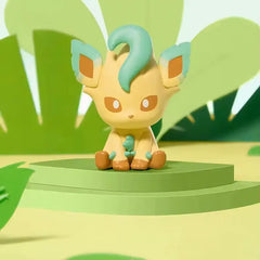 "Figurine aléatoire de l'évolution Eeveelution Mini Figure Blind Box, représentant Leafeon assis sur une plateforme verte dans la nature."
